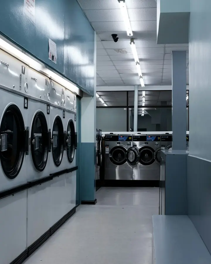 Deretan mesin cuci dan pengering di sebuah laundry.