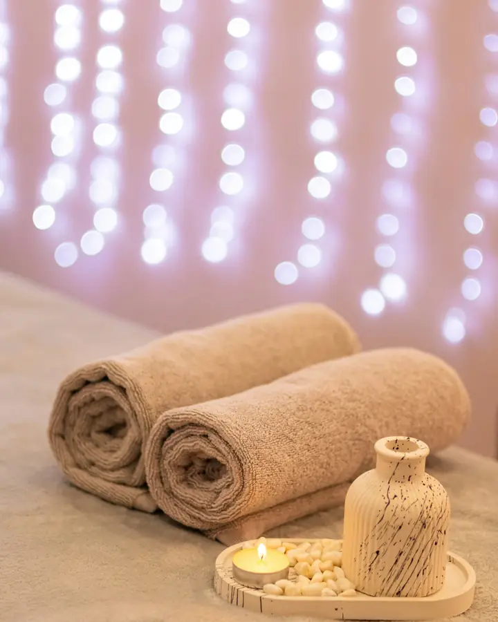 Handuk yang digulung dan lilin aromaterapi di ruang spa.